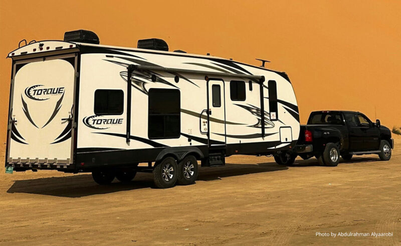 A large toy hauler trailer in front of a sand dune